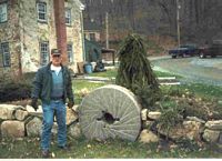 Gene Doerflinger standing in the side yard next to the millstone at the Kummerer house